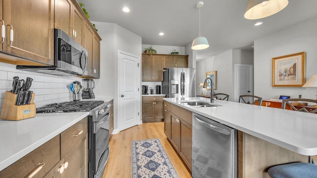 2824 Granite Ct, Sheboygan, WI 53081 - kitchen featuring stainless steel appliances, light wood finished floors, light countertops, hanging light fixtures, and backsplash