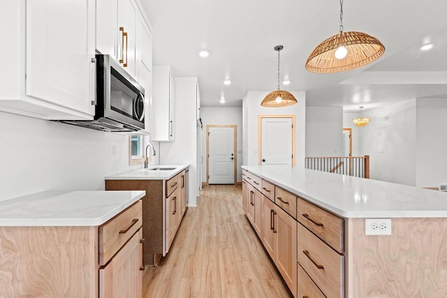 399 Battery Ave, De Pere, WI 54115 - kitchen featuring stainless steel microwave, light wood finished floors, a center island, light stone counters, and hanging light fixtures