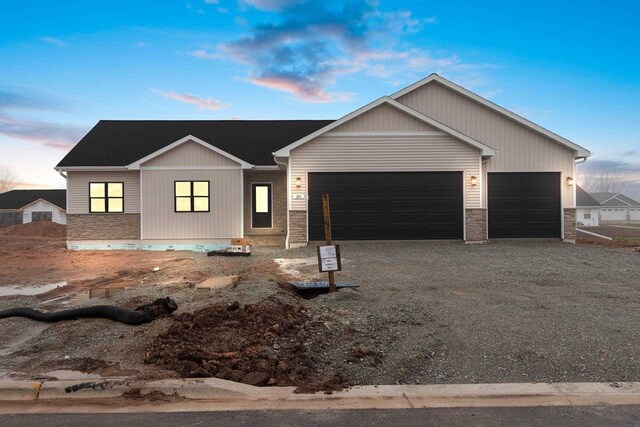 399 Battery Ave, De Pere, WI 54115 - view of front of house featuring a garage, stone siding, and gravel driveway