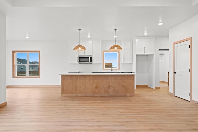 399 Battery Ave, De Pere, WI 54115 - kitchen with stainless steel microwave, recessed lighting, light wood-style flooring, white cabinets, and a center island
