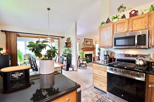 2360 Cobblestone Ln, Beloit, WI 53511 - kitchen with appliances with stainless steel finishes, dark countertops, vaulted ceiling, a fireplace, and decorative light fixtures