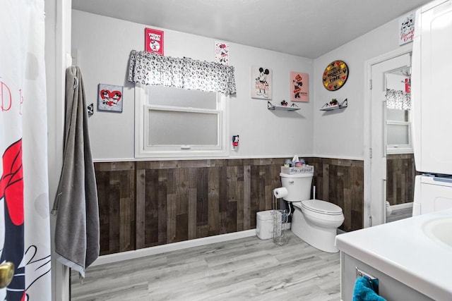 814 Quinney Ave, Kaukauna, WI 54130 - bathroom with stacked washing machine and dryer, a wainscoted wall, vanity, and wood finished floors