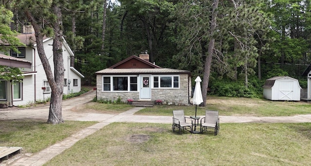 N2817 Rustic Dr, Clintonville, WI 54929 - view of front of house with stone siding, entry steps, a chimney, a front lawn, and a shed