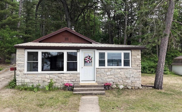 N2817 Rustic Dr, Clintonville, WI 54929 - bungalow-style house featuring stone siding, a metal roof, a front yard, entry steps, and board and batten siding