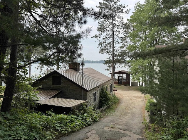 N2817 Rustic Dr, Clintonville, WI 54929 - view of side of home with a chimney, stone siding, a metal roof, a standing seam roof, and a water view