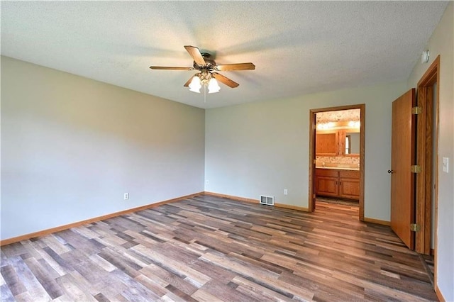 W5342 County Highway F, Trego, WI 54888 - unfurnished bedroom with wood finished floors, a textured ceiling, connected bathroom, and a ceiling fan