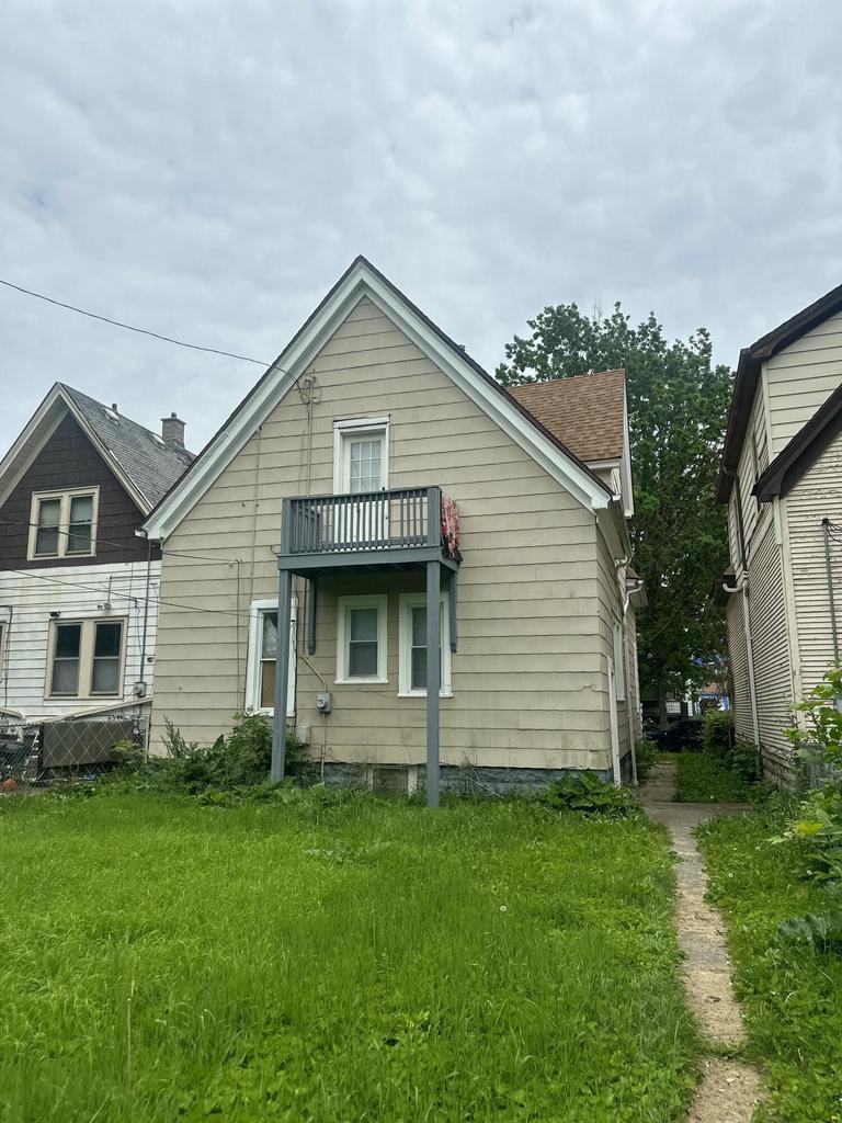 2843 N 25th St, Milwaukee, WI 53206 - rear view of property with a balcony, a shingled roof, and a lawn