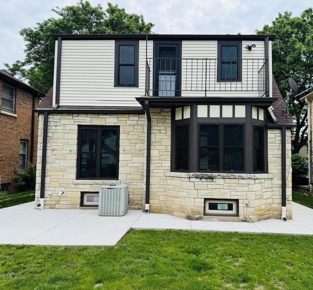 3441 N 55th St, Milwaukee, WI 53216 - rear view of house with a balcony, stone siding, a patio area, and a lawn