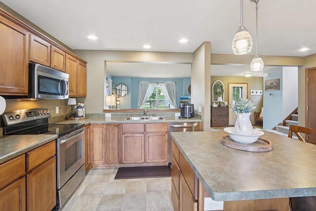 7042 Littlemore Dr, Madison, WI 53718 - kitchen featuring appliances with stainless steel finishes, brown cabinets, a center island, hanging light fixtures, and recessed lighting