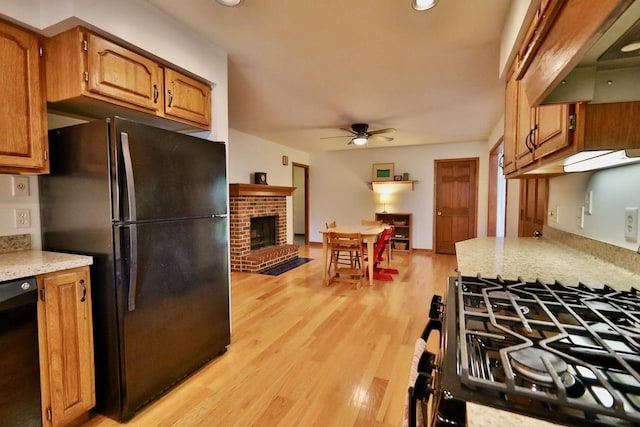 2413 Ravenswood Rd, Madison, WI 53711 - kitchen featuring black appliances, ceiling fan, custom exhaust hood, light wood-style floors, and a brick fireplace