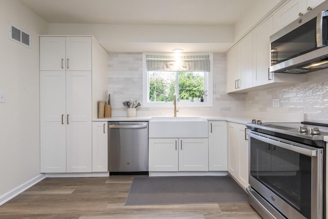 8725 N Fielding Rd, Bayside, WI 53217 - kitchen featuring stainless steel appliances, backsplash, white cabinets, and light countertops