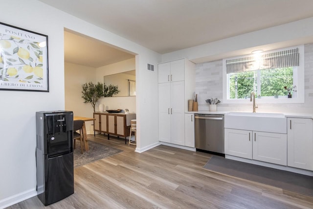 8725 N Fielding Rd, Bayside, WI 53217 - kitchen featuring stainless steel dishwasher, light wood-style floors, light countertops, and white cabinetry
