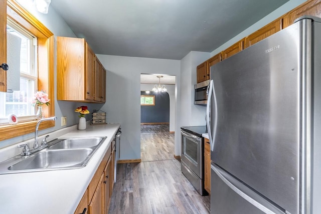 2941 Plover Rd, Wisconsin Rapids, WI 54494 - kitchen featuring appliances with stainless steel finishes, wood finished floors, brown cabinets, light countertops, and a chandelier