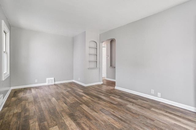 4636 N 19th St, Milwaukee, WI 53209 - spare room featuring arched walkways, dark wood finished floors, and built in shelves