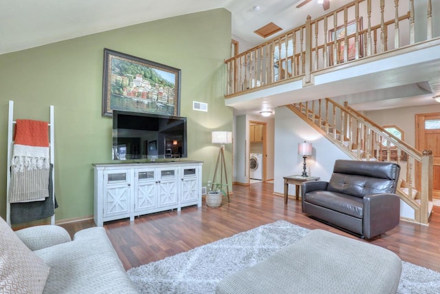 W227N2527 Meadowood Ln, Waukesha, WI 53186 - living room featuring washer / dryer, stairway, wood finished floors, ceiling fan, and high vaulted ceiling