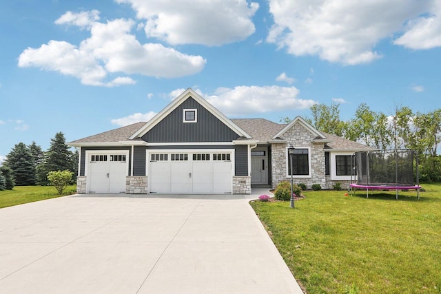 2322 Kae Ct, Mount Pleasant, WI 53406 - craftsman-style house with stone siding, board and batten siding, a garage, a front lawn, and a trampoline