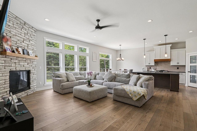 2322 Kae Ct, Mount Pleasant, WI 53406 - living area with a ceiling fan, dark wood-type flooring, a stone fireplace, recessed lighting, and a chandelier