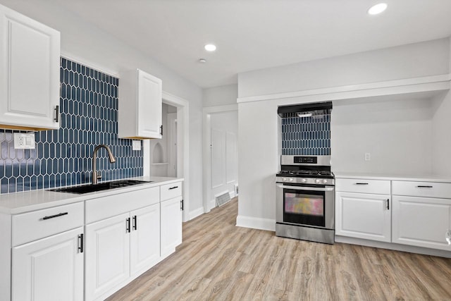 4423 N 30th St Unit 4425, Milwaukee, WI 53209 - kitchen featuring gas range, light countertops, tasteful backsplash, light wood-style floors, and white cabinets