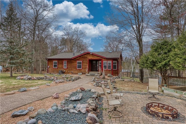 7766 Thunder Point Rd, Hayward, WI 54843 - log cabin featuring an outdoor fire pit, a patio area, and roof with shingles