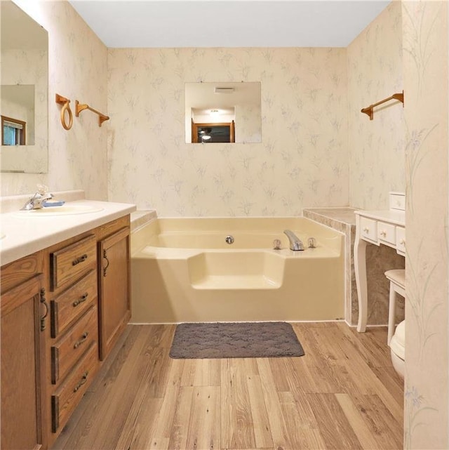 112 S 3rd St, Luck, WI 54853 - bathroom featuring wood finished floors, wallpapered walls, vanity, and a garden tub