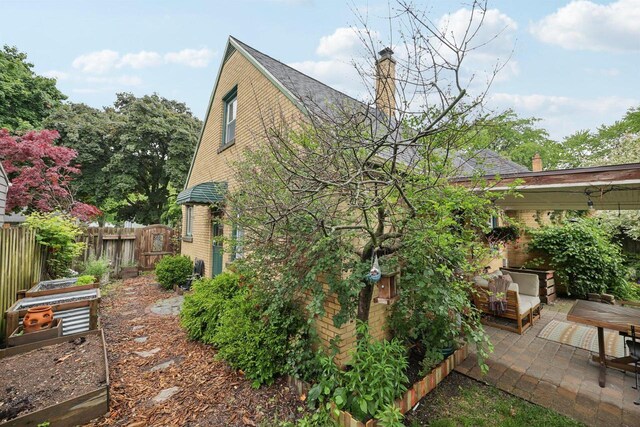 3154 N 82nd St, Milwaukee, WI 53222 - view of side of home featuring a patio, a chimney, a garden, and brick siding