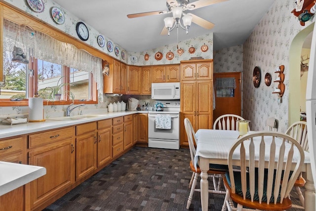 230 Gilbertson St, Markesan, WI 53946 - kitchen with white appliances, wallpapered walls, ceiling fan, light countertops, and brown cabinets