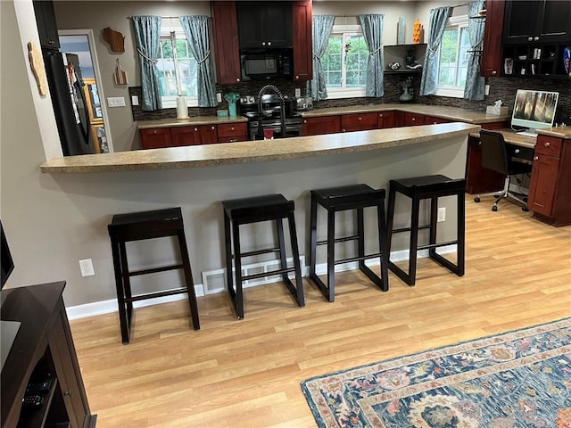 3158 Leslie Ln, Eau Claire, WI 54703 - kitchen with black appliances, light wood-style floors, a kitchen bar, and backsplash