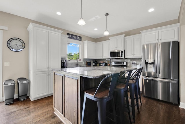 1395 American Eagle Dr, Slinger, WI 53086 - kitchen featuring appliances with stainless steel finishes, light stone counters, white cabinetry, tasteful backsplash, and recessed lighting