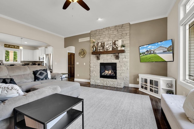 1395 American Eagle Dr, Slinger, WI 53086 - living room with crown molding, a ceiling fan, dark wood finished floors, arched walkways, and a stone fireplace
