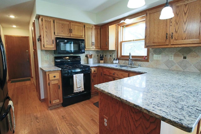 1000 Ridge Rd, Waukesha, WI 53186 - kitchen with black appliances, light wood-style floors, a peninsula, brown cabinetry, and pendant lighting