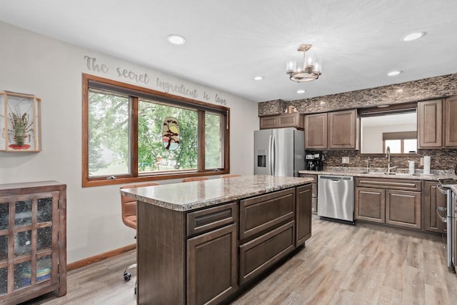 915 Nelson Ave, Milton, WI 53563 - kitchen with stainless steel appliances, light wood-type flooring, a kitchen island, decorative backsplash, and a chandelier