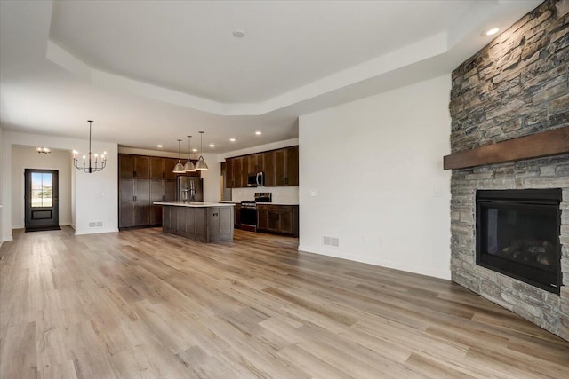 516 Hickory Hollow Rd Unit 0402, Waterford, WI 53185 - unfurnished living room with a tray ceiling, a chandelier, recessed lighting, light wood finished floors, and a fireplace