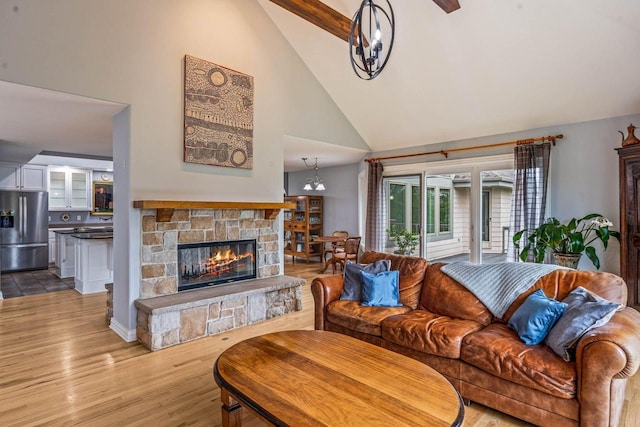 N66W38493 N Woodlake Cir, Oconomowoc, WI 53066 - living room featuring high vaulted ceiling, a stone fireplace, wood finished floors, and a chandelier