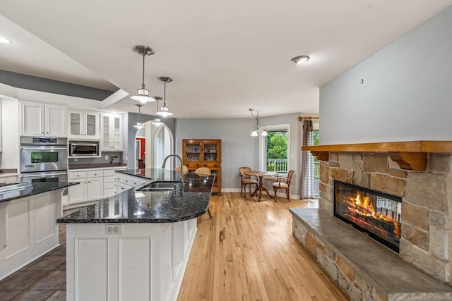 N66W38493 N Woodlake Cir, Oconomowoc, WI 53066 - kitchen featuring stainless steel appliances, white cabinets, glass insert cabinets, a fireplace, and dark stone counters