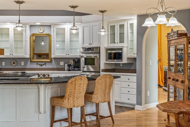 N66W38493 N Woodlake Cir, Oconomowoc, WI 53066 - kitchen with stainless steel appliances, a breakfast bar area, white cabinets, and light wood-style flooring