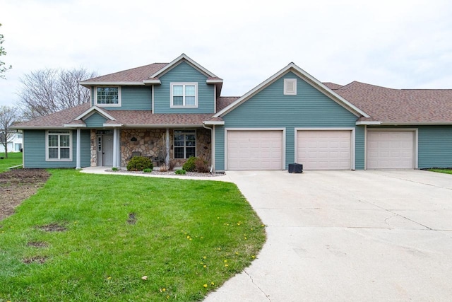 180 E River Dr, De Pere, WI 54115 - traditional-style house featuring a garage, a front lawn, concrete driveway, roof with shingles, and stone siding