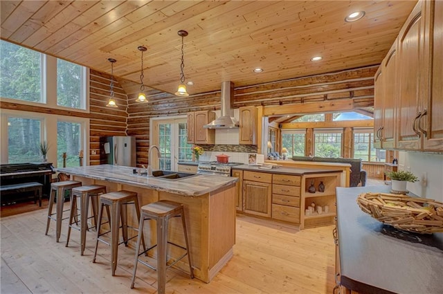 14097 W State Road 77, Hayward, WI 54843 - kitchen with wall chimney exhaust hood, wooden ceiling, log walls, a center island with sink, and light wood-type flooring