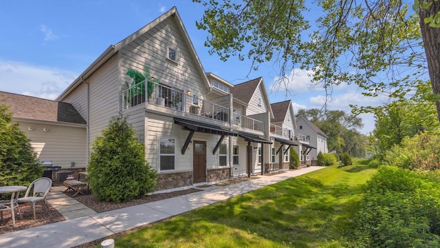 814 N 15th St Unit B, Sheboygan, WI 53081 - rear view of house with a balcony, a lawn, and stone siding
