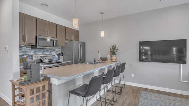 814 N 15th St Unit B, Sheboygan, WI 53081 - kitchen with appliances with stainless steel finishes, a breakfast bar, a peninsula, and light wood-style floors
