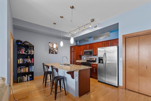106 W Seeboth St Unit 702, Milwaukee, WI 53204 - kitchen with stainless steel appliances, light wood-type flooring, a breakfast bar, tasteful backsplash, and light stone countertops