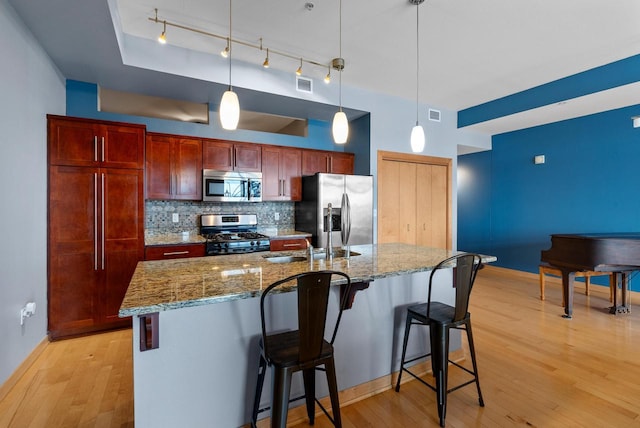 106 W Seeboth St Unit 702, Milwaukee, WI 53204 - kitchen with appliances with stainless steel finishes, light wood-style floors, decorative backsplash, and a breakfast bar