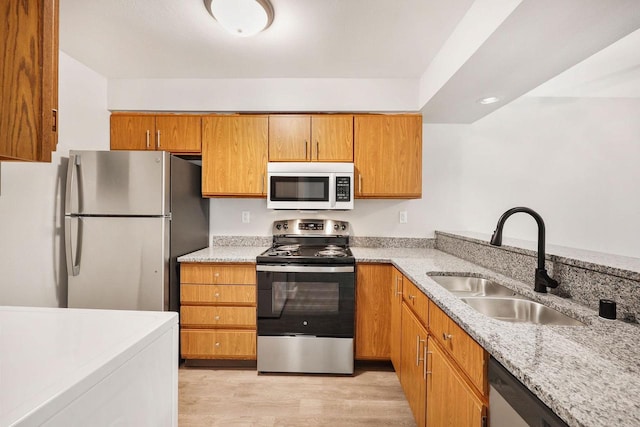 807 Whispering Pines Way, Fitchburg, WI 53713 - kitchen with stainless steel appliances, light wood-style floors, light stone countertops, brown cabinetry, and recessed lighting