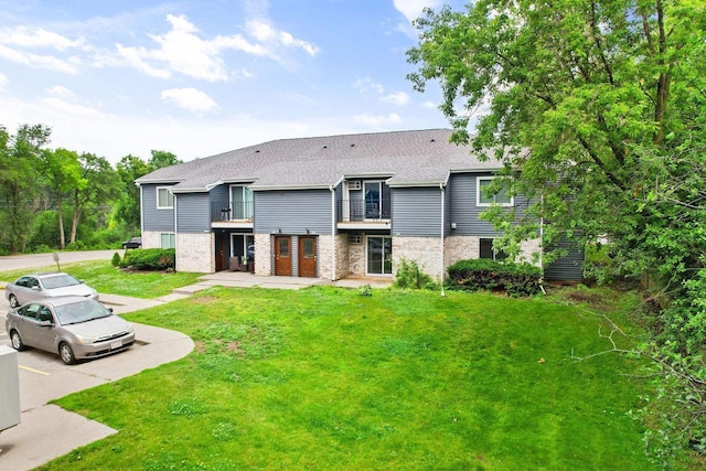 807 Whispering Pines Way, Fitchburg, WI 53713 - rear view of property featuring a balcony, a shingled roof, brick siding, and a yard