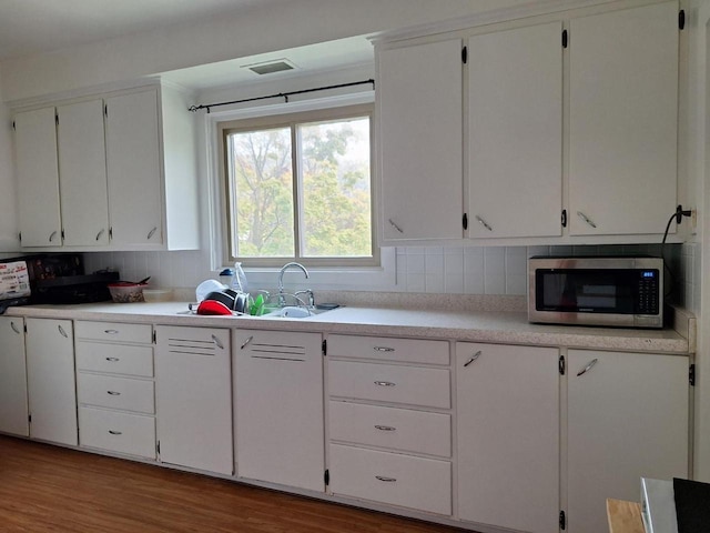 1744 N 27th St, Sheboygan, WI 53081 - kitchen featuring stainless steel microwave, light countertops, wood finished floors, and white cabinets