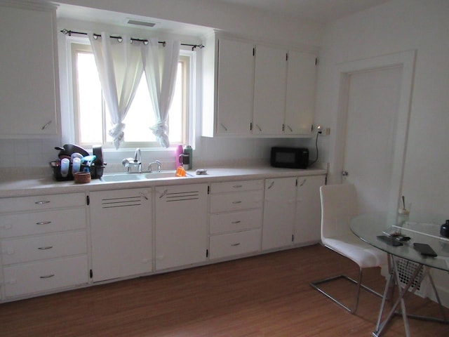 1744 N 27th St, Sheboygan, WI 53081 - kitchen featuring black microwave, light wood finished floors, white cabinets, and light countertops