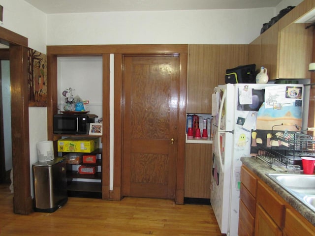 616 N 14th St, Sheboygan, WI 53081 - kitchen featuring black microwave, light wood-type flooring, brown cabinets, and freestanding refrigerator