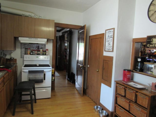 616 N 14th St, Sheboygan, WI 53081 - kitchen with white electric range, under cabinet range hood, light wood-type flooring, and brown cabinetry
