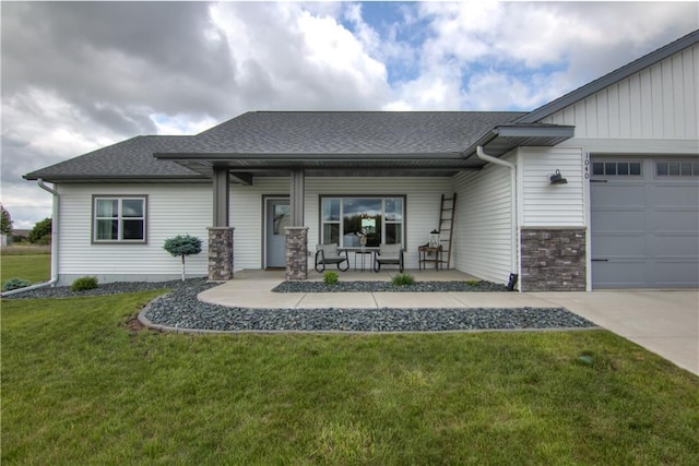 1040 Wissota Green Pkwy, Chippewa Falls, WI 54729 - view of front of home with a front yard, an attached garage, a shingled roof, covered porch, and stone siding