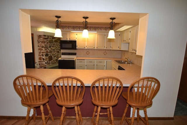 3917 Ross Ave, Weston, WI 54401 - kitchen with black microwave, white range with electric cooktop, backsplash, light countertops, and a peninsula