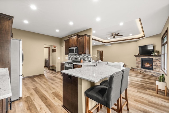 3830 Augusta Ct, Plover, WI 54467 - kitchen featuring appliances with stainless steel finishes, a ceiling fan, a peninsula, dark brown cabinets, and a tray ceiling
